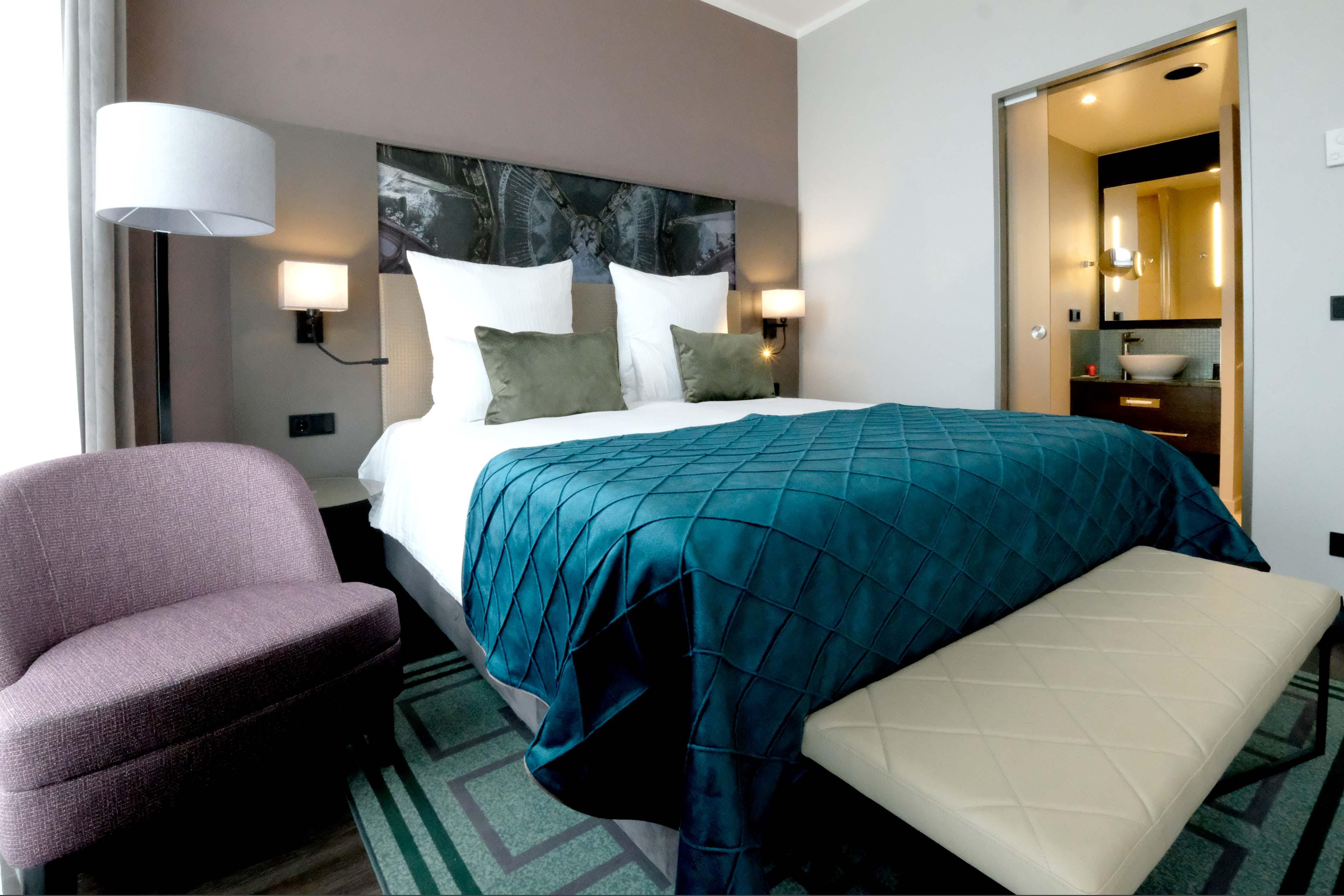 Gedämpfte Farben und ein Bad, in das durch die Milchglastür auch Tageslicht fällt: So sehen die Hotelzimmer aus.