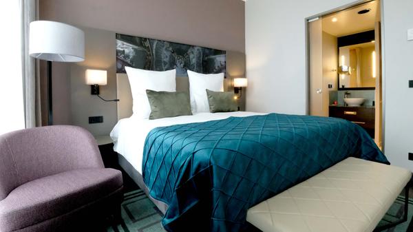 Gedämpfte Farben und ein Bad, in das durch die Milchglastür auch Tageslicht fällt: So sehen die Hotelzimmer aus.