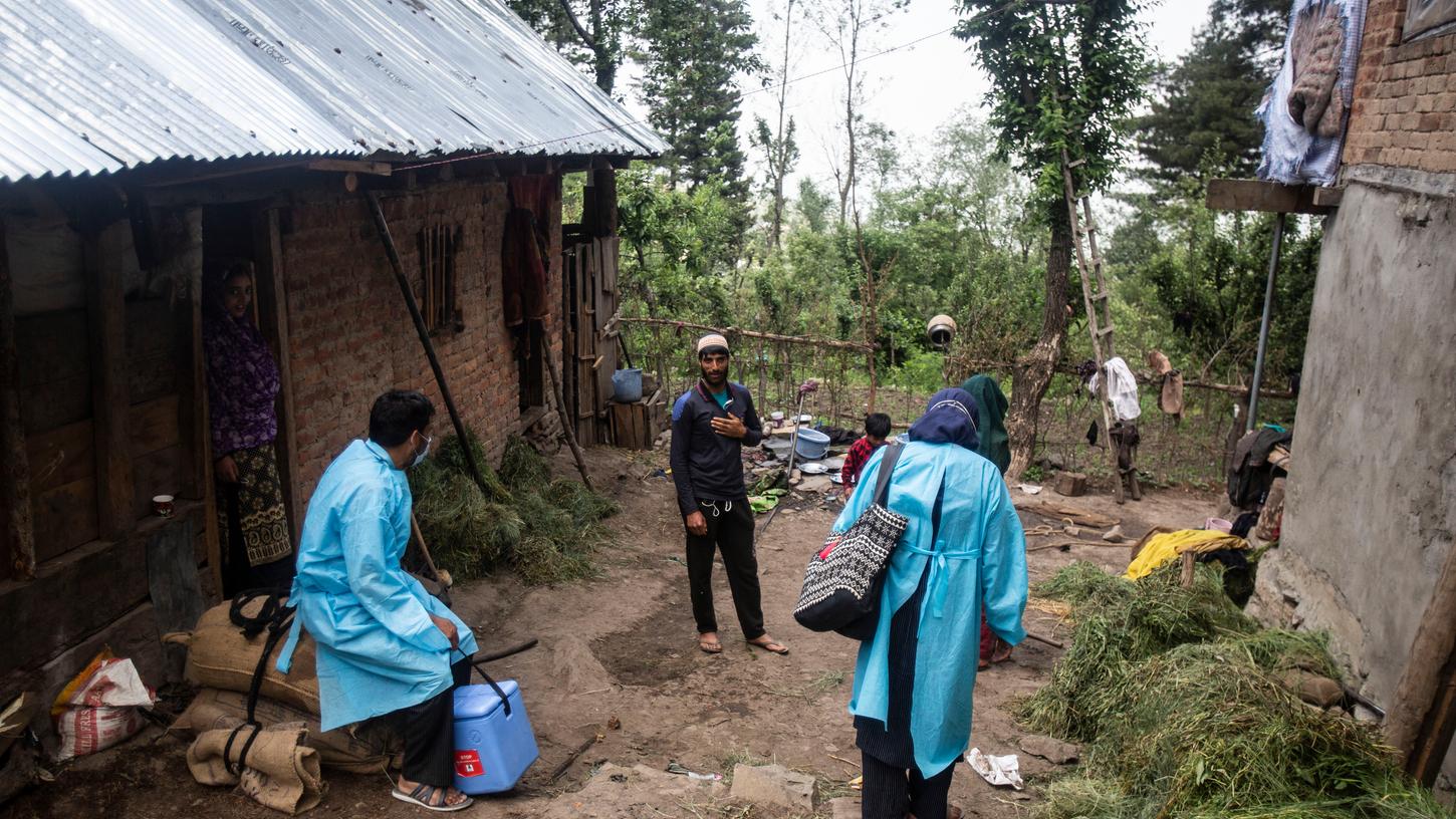 Mitarbeiter des Gesundheitswesens sprechen mit Dorfbewohnern, um sie von einer Impfung gegen das Coronavirus zu überzeugen.