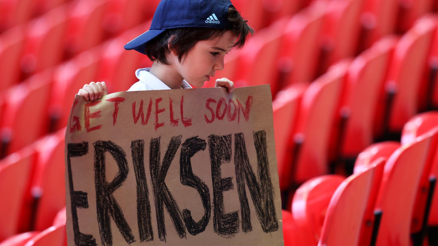 Ein junger Fan sendet dem Dänischen Nationalspieler Eriksen mit einem Plakat Genesungswünsche aus dem Wembley Stadion in London.
Ein junger Fan sendet dem Dänischen Nationalspieler Eriksen mit einem Plakat Genesungswünsche aus dem Wembley Stadion in London.