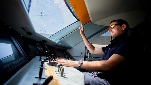 Kevin Tinney, Ausbilder für Lokführer bei der Deutschen Bahn, hebt die Hand, als er einen ICE 2 ins ICE-Werk Rummelsburg fährt.