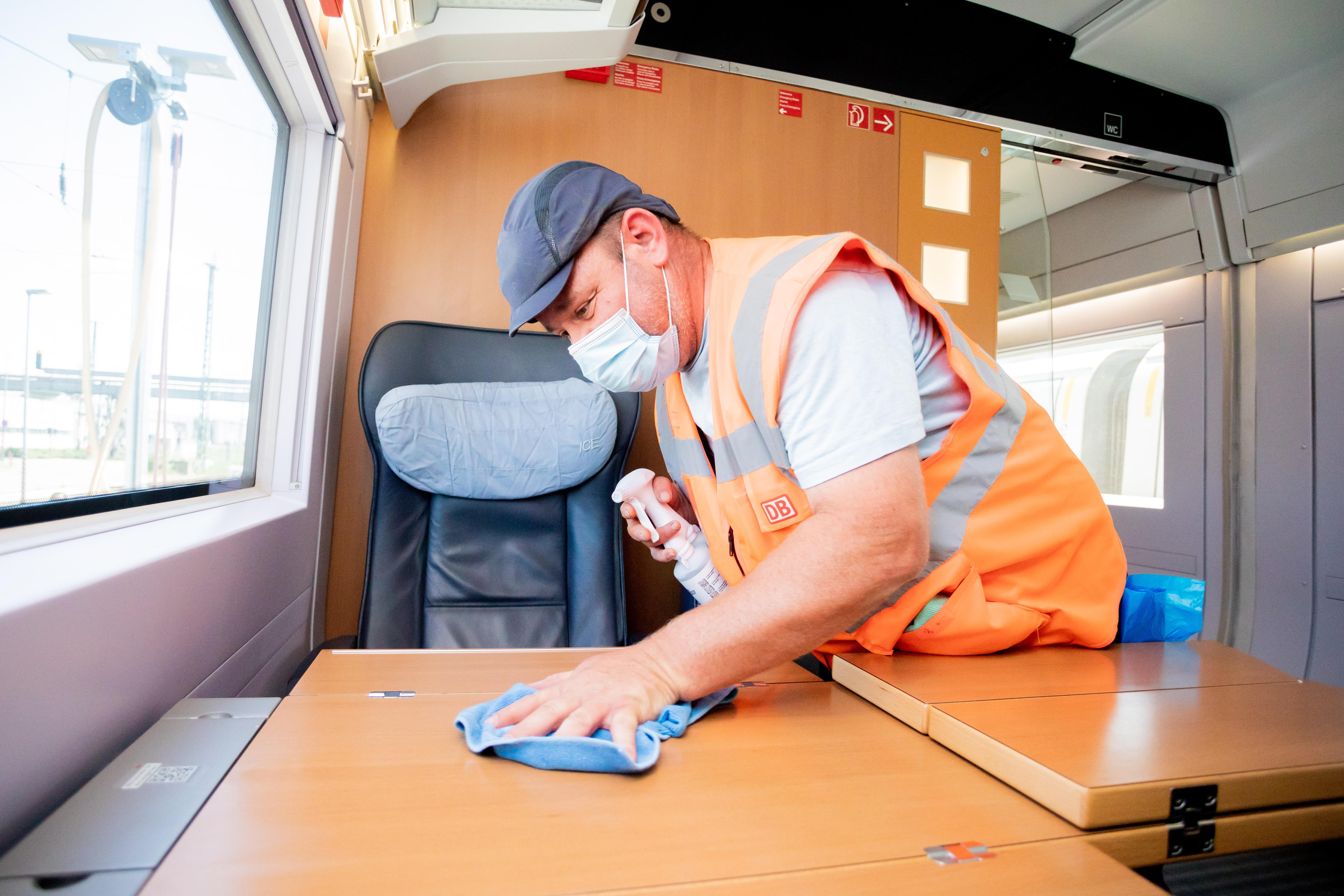 Marcel Ballin, Schichtleiter für die Fahrzeugreinigung, reinigt in einem ICE einen Tisch, als dieser im ICE-Werk Rummelsburg zur Reinigung Zwischenhalt macht.