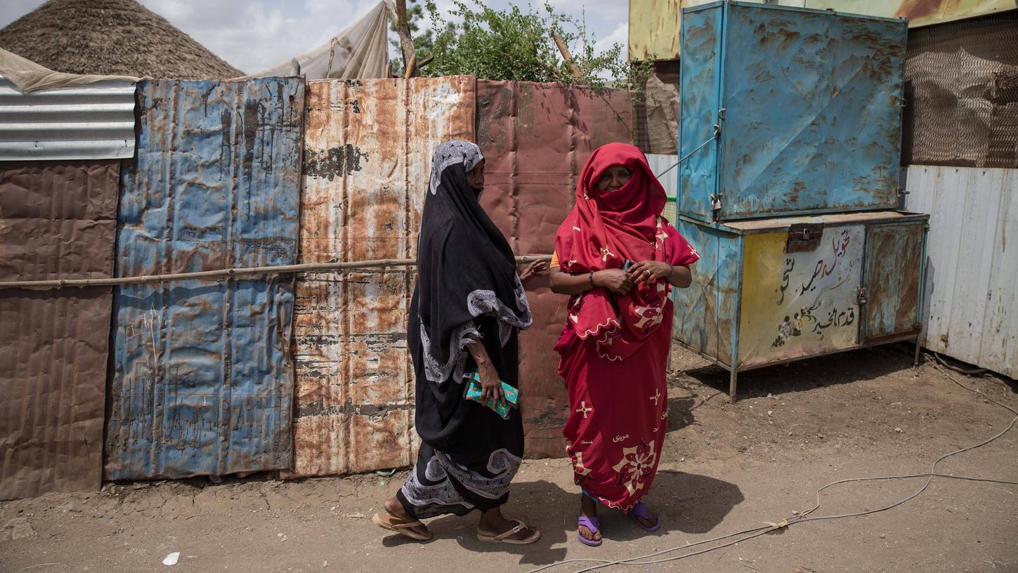 Frauen stehen vor einer notdürftig zusammengezimmerten Unterkunft im Flüchtlingslager Shagarab im Sudan.
