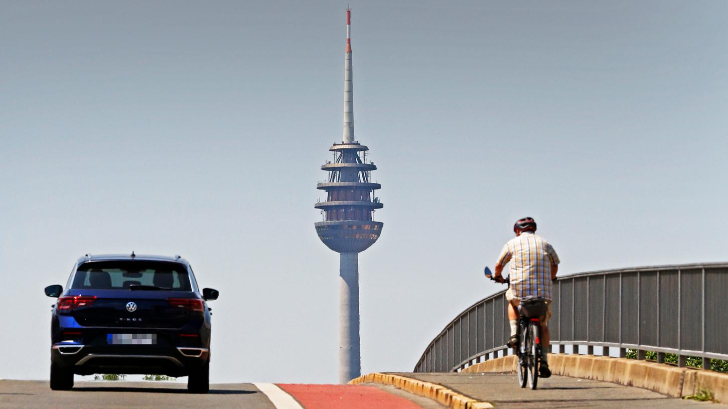 Steht seit ein paar Monaten unter Denkmalschutz: der Nürnberger Fernmeldeturm, hier steuern ein Auto- und Radfahrer auf der "Siemensbrücke" in Steinbühl auf ihn zu.