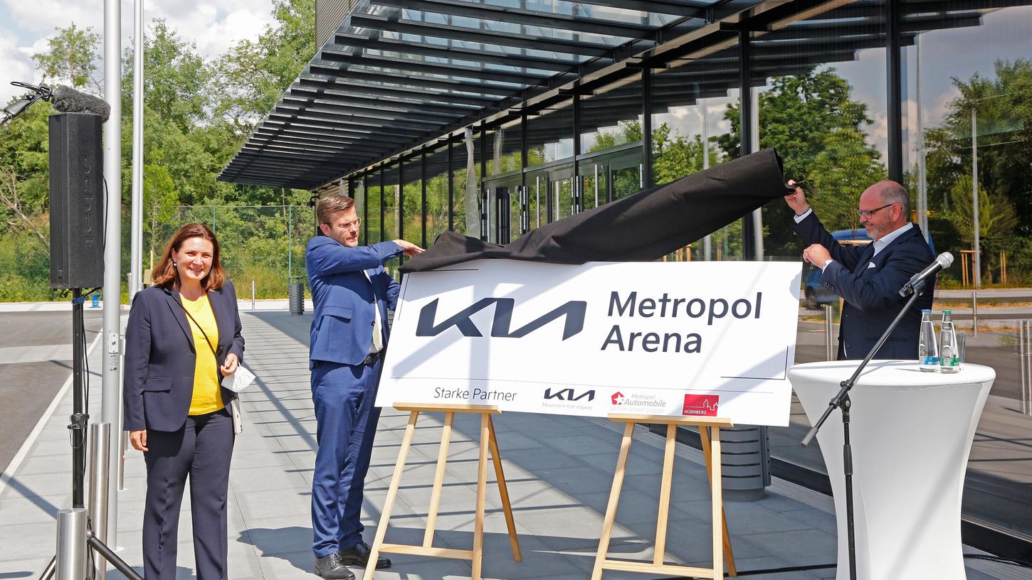 So wird es bald auf dem Dach des Neubaus am Tillypark stehen: Sportreferentin Cornelia Trinkl, OB Marcus König und Sponsor Jochen Scharf (v.l.n.r.) enthüllen das Namensschild der neuen Kia Metropol Arena.