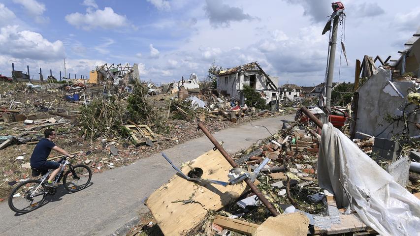 Ein Mann fährt im Juni 2021 mit seinem Fahrrad auf einer Straße vorbei an den Trümmern zerstörter und stark beschädigter Gebäude im tschechischen Dorf Mikulcice.