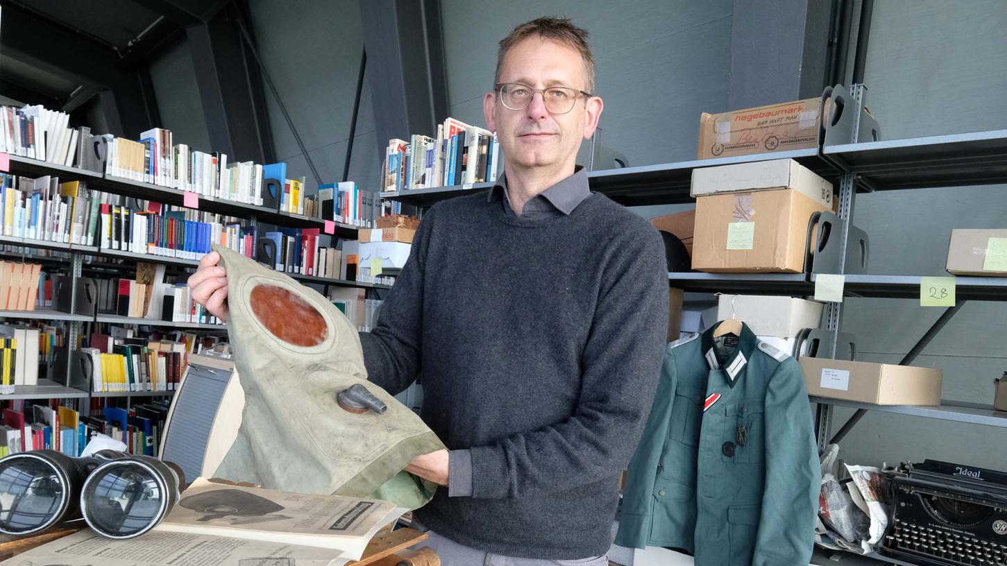 Im Zwischendepot: Alexander Schmidt, Mitarbeiter des Dokuzentrums, mit einem „Gasjäckchen“ für Kleinkinder. Derzeit werden die unzähligen Objekte geordnet und digitalisiert.
Im Zwischendepot: Alexander Schmidt, Mitarbeiter des Dokuzentrums, mit einem „Gasjäckchen“ für Kleinkinder. Derzeit werden die unzähligen Objekte geordnet und digitalisiert.