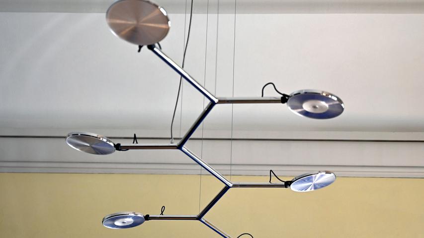 Zum modernen Gestühl gehören auch moderne Lampen. Statt eines Kronleuchters beleuchtet eine Designer-Lampe aus Metall und Glas den großen Konferenztisch.

