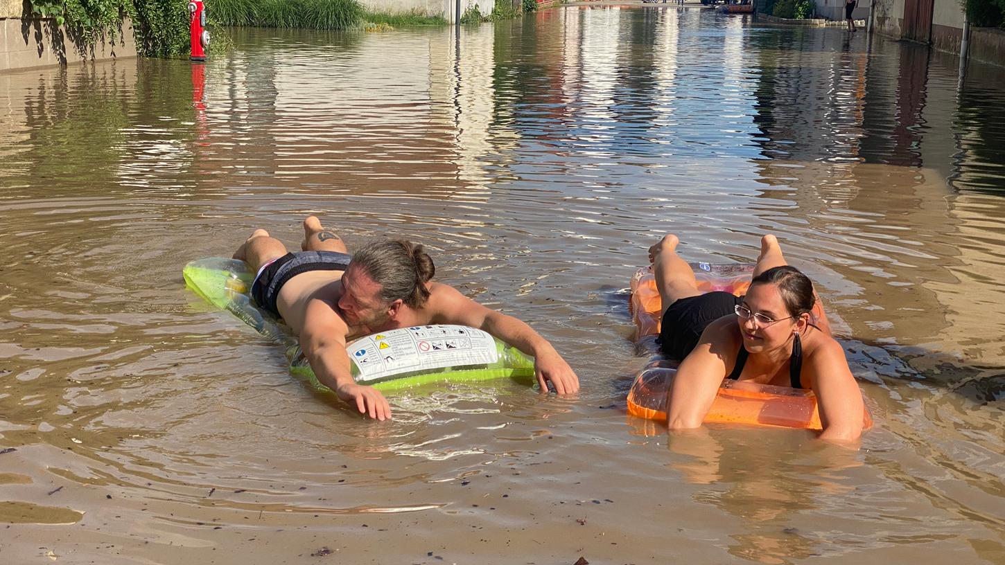 In Willersdorf haben sich die Leute kurzerhand ihre Luftmatratze und ein Bier geschnappt und sind damit nun auf dem Hochwasser unterwegs. Während auch dort zahlreiche Einsatzkräfte gegen die Wassermengen kämpfen, warten einige am Samstagnachmittag einfach darauf, bis es von alleine wieder weggeht und genießen die Sonnenstrahlen nach dem heftigen Regenwetter.