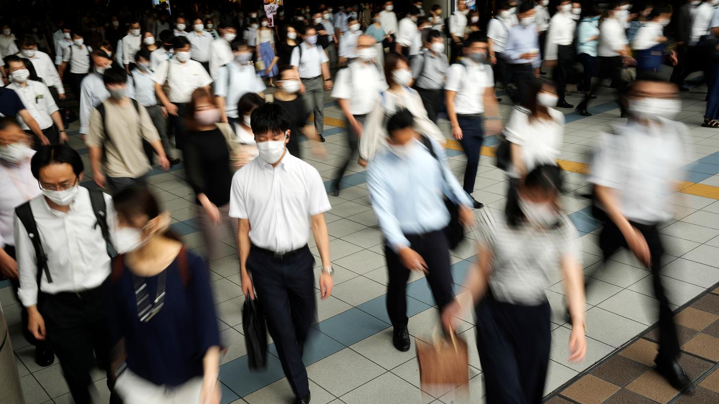 Pendler mit Gesichtsmasken gehen in einem Durchgang während der Hauptverkehrszeit am Shinagawa Bahnhof. Japan erklärte den vierten Ausnahmezustand für Tokio von Montag bis zum 22. August. 