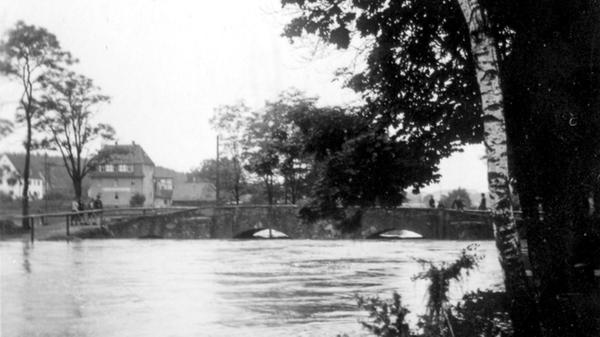 Nach tagelangem Regen war der Pegel der Aurach stark angestiegen. Ein im Talkessel der Nutzung niedergegangener Sturzregen verursachte den Bruch des Dammes am Wiwaweiher. Hier ist die Steinerne Brücke in Herzogenaurach zu sehen.