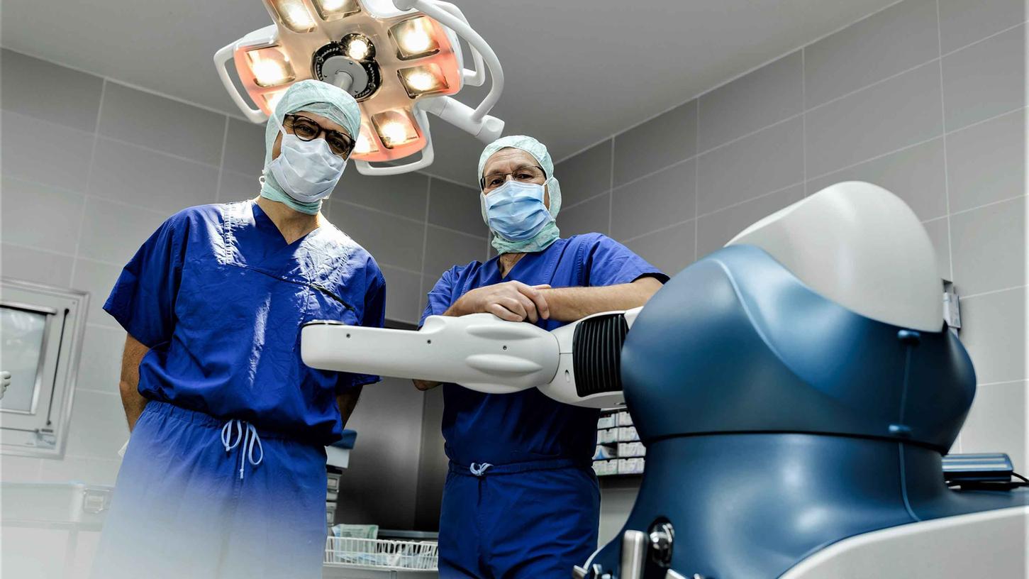 Die beiden Fachärzte Chefarzt Dr. med. Mathias Bender (rechts) sowie Oberarzt Dr. Nikolaj Vasak mit dem OP-Roboter im Operationssaal.
Die beiden Fachärzte Chefarzt Dr. med. Mathias Bender (rechts) sowie Oberarzt Dr. Nikolaj Vasak mit dem OP-Roboter im Operationssaal.