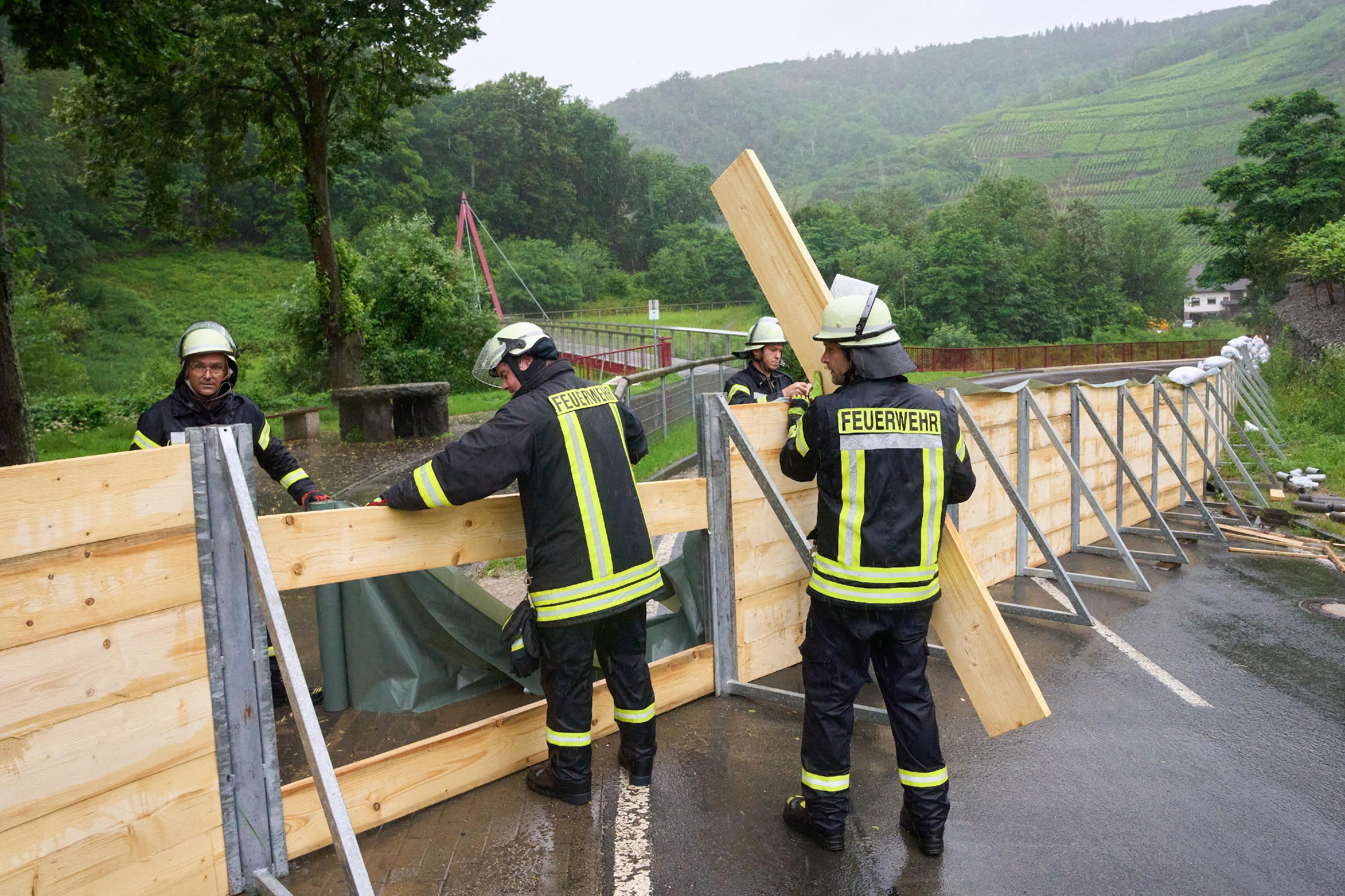 Feuerwehrleute haben im Ahrtal bei Mayschoss eine Sperrwand aus Holz errichtet, um zu verhindern, dass das Hochwasser der Ahr in den Ort läuft.
