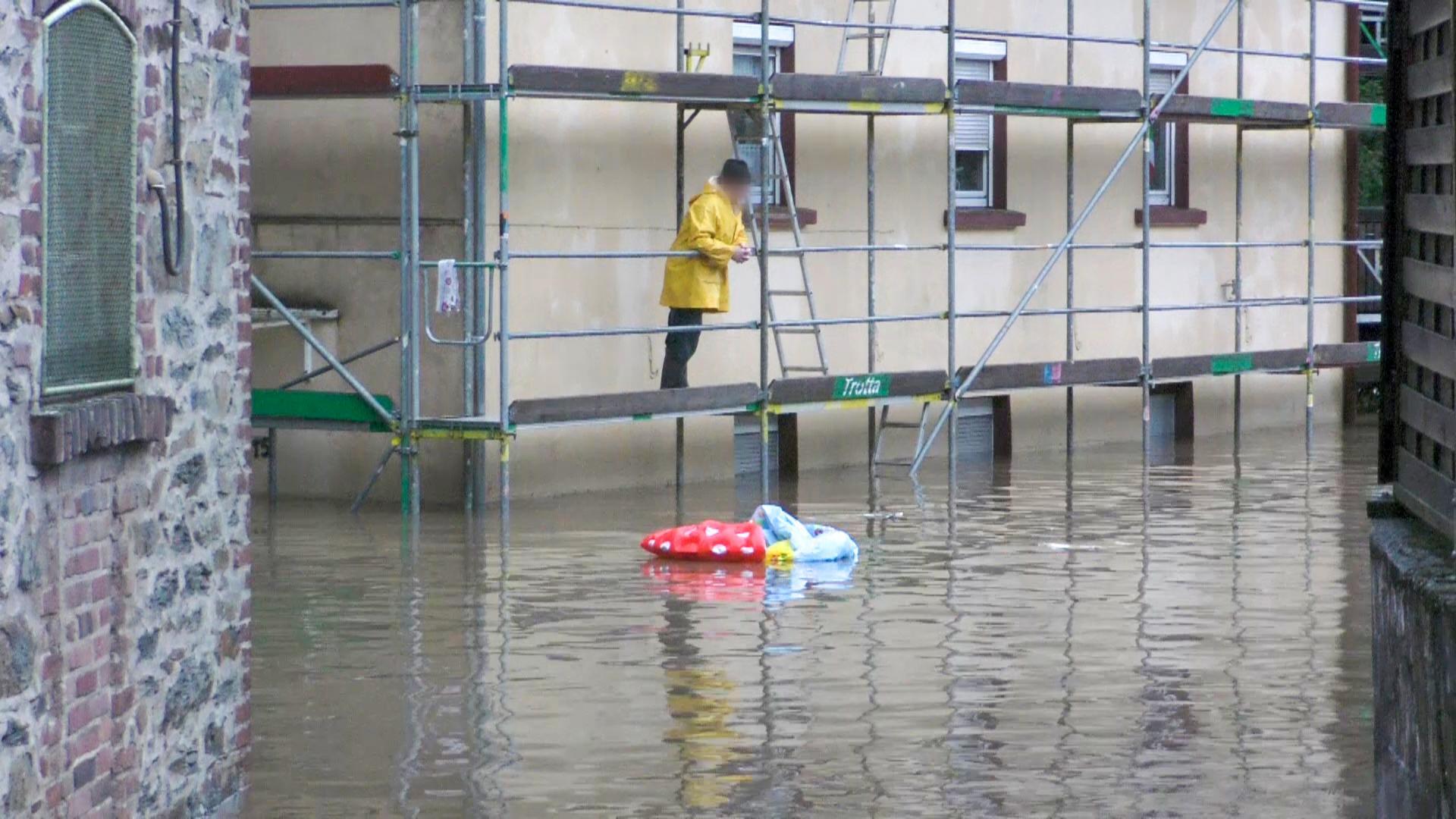 Ein Mann betrachtet die geflutete Straße unter ihm. 