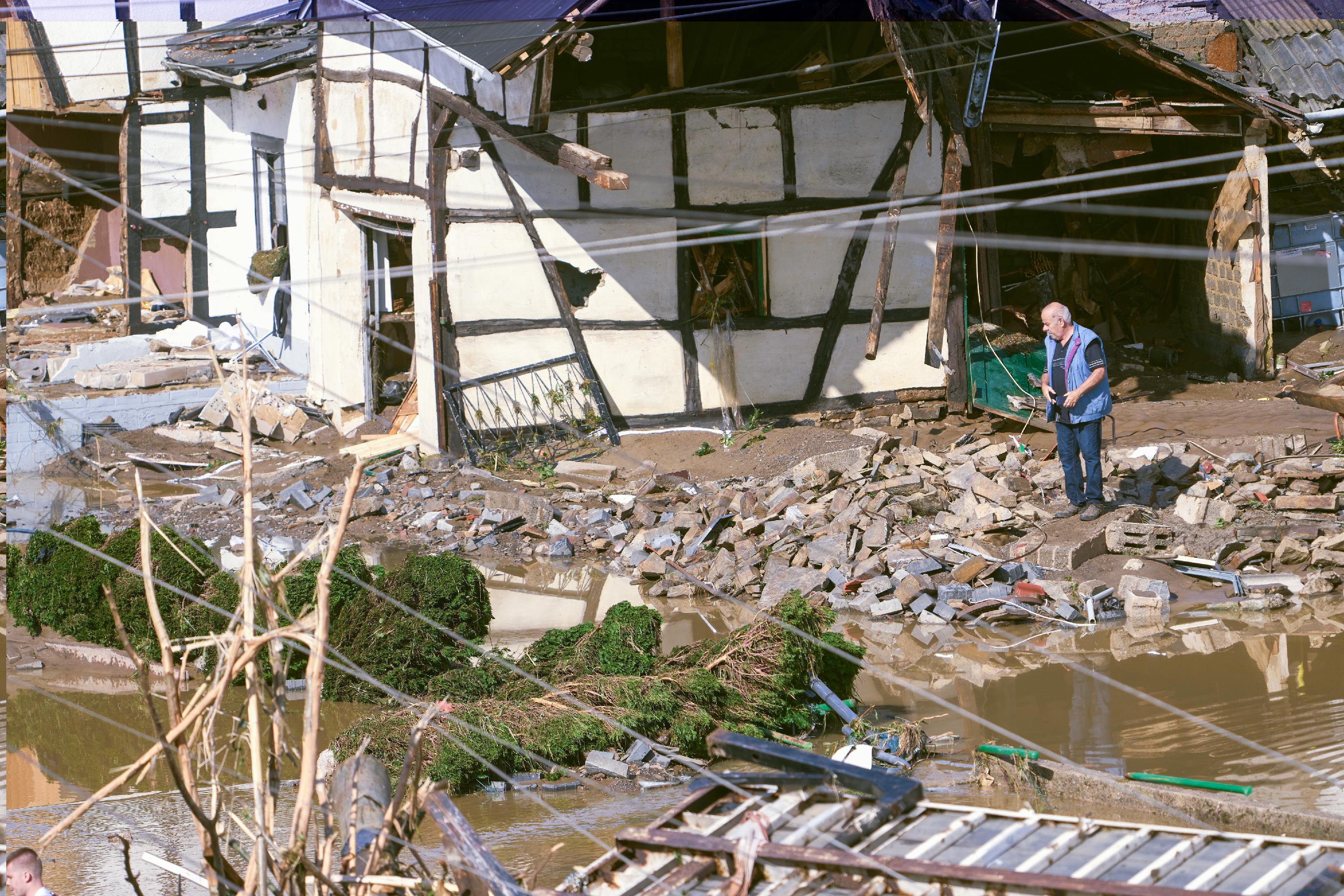 Ein Mann begutachtet das Chaos im Dorf Schuld im Kreis Ahrweiler.