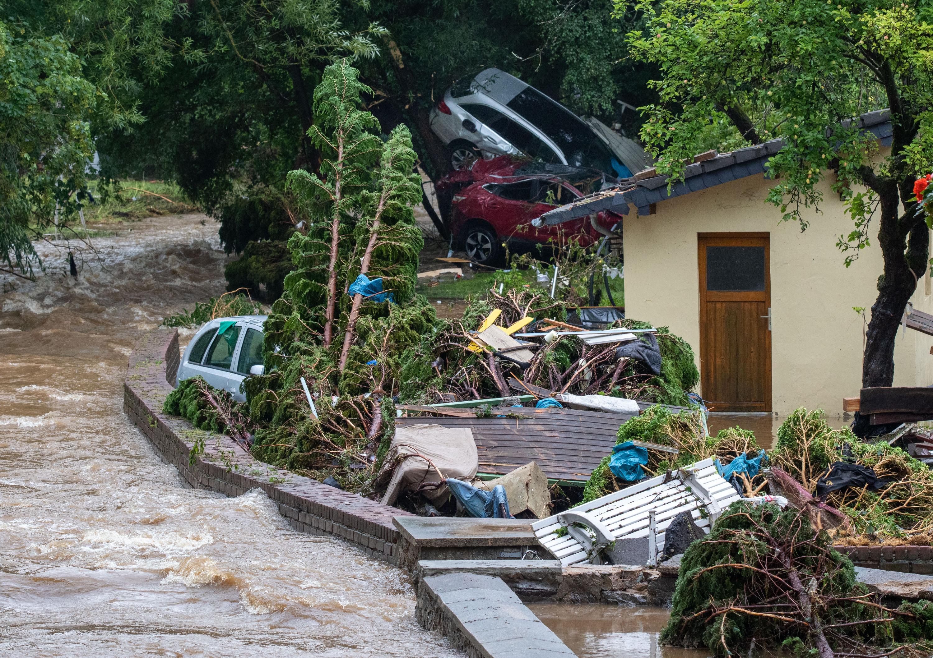 Das Wasser fließt die Straße entlang, zerdrückte Autos liegen auf einer Zufahrt.In Nordrhein-Westfalen war der Vichtbach über die Ufer getreten.