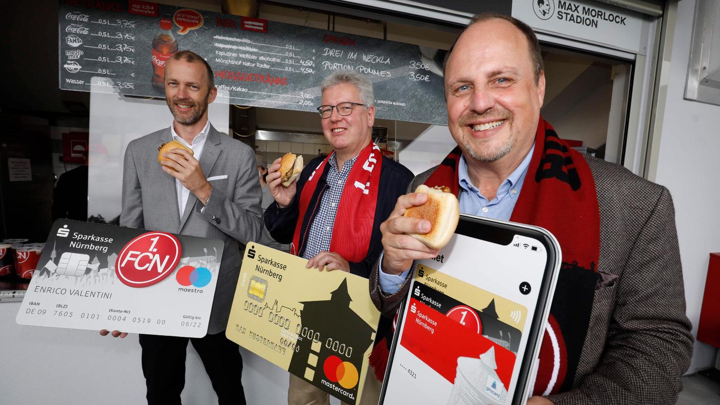 Die erste mobile bezahlte Bratwurst ging am Samstag beim Club über den Tresen - Niels Rossow vom 1. FC Nürnberg, Matthias Everding von der Sparkasse und Bürgermeister Christian Vogel (von links) ließen es sich schmecken.