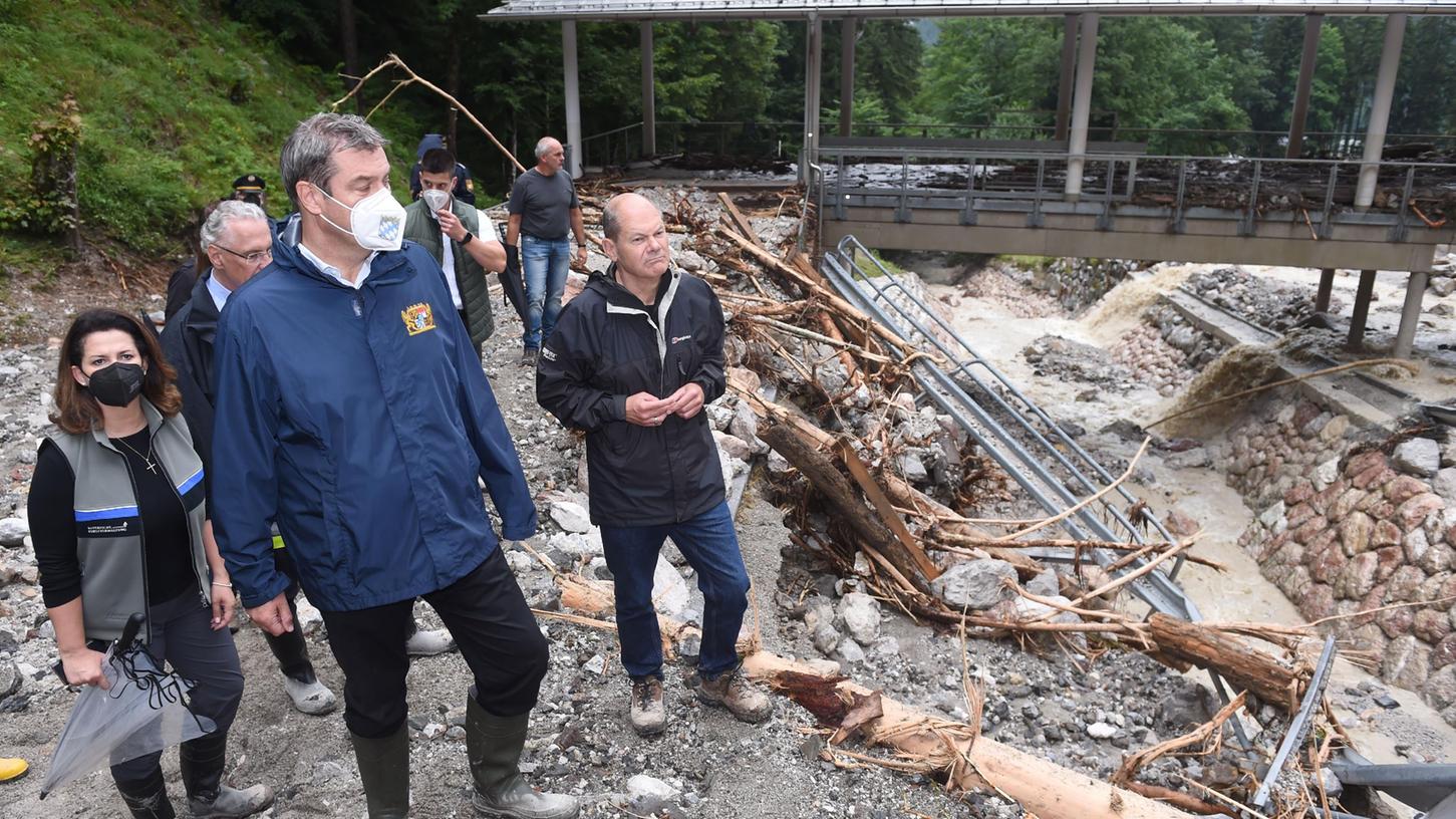 Markus Söder (M), Olaf Scholz (r., SPD) und Michaela Kaniber (l., CSU), stehen bei der durch Unwetter zerstörten Bob- und Rodelbahn am Königssee.