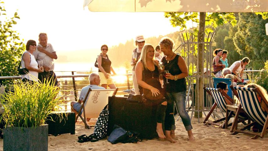 Schlemmen inmitten von zwei fränkischen Seen: Auf der Biergarten-Terrasse von Sand&Sofa in Enderndorf ist das möglich, denn die Location vergönnt einen direkten Blick auf den Igelsbachsee und ist nur einen Steinwurf vom Brombachsee entfernt. Abends kann man hier zum Sonnenuntergang Pizza und Wein genießen - oft bei Live-Musik. Currywurst und Schnitzelsandwich gehören aber ebenso zum Repertoire wie Salatteller oder ein Eiskaffee. Schlemmen inmitten von zwei fränkischen Seen: Auf der Biergarten-Terrasse von Sand&Sofa in Enderndorf ist das möglich, denn die Location vergönnt einen direkten Blick auf den Igelsbachsee und ist nur einen Steinwurf vom Brombachsee entfernt. Abends kann man hier zum Sonnenuntergang Pizza und Wein genießen - oft bei Live-Musik. Currywurst und Schnitzelsandwich gehören aber ebenso zum Repertoire wie Salatteller oder ein Eiskaffee.