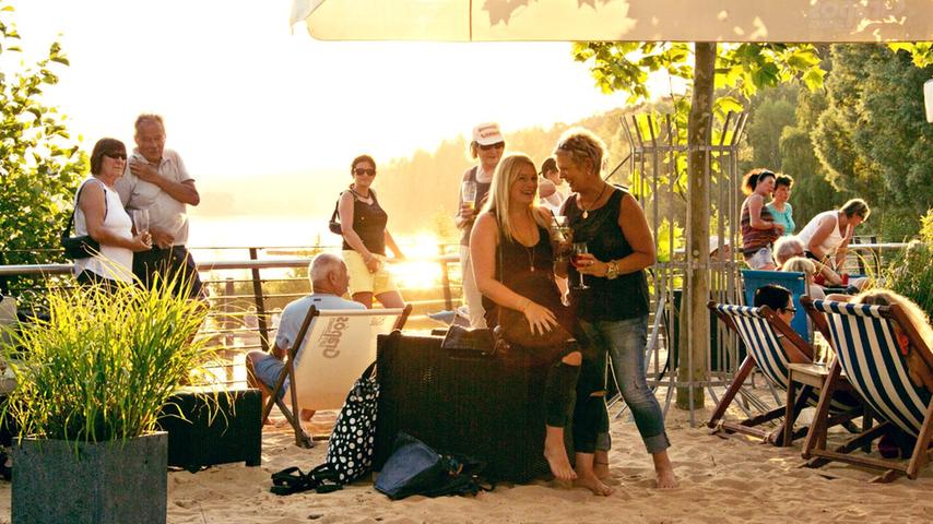 Schlemmen inmitten von zwei fränkischen Seen: Auf der Biergarten-Terrasse von Sand&Sofa in Enderndorf ist das möglich, denn die Location vergönnt einen direkten Blick auf den Igelsbachsee und ist nur einen Steinwurf vom Brombachsee entfernt. Abends kann man hier zum Sonnenuntergang Pizza und Wein genießen - oft bei Live-Musik. Currywurst und Schnitzelsandwich gehören aber ebenso zum Repertoire wie Salatteller oder ein Eiskaffee. 