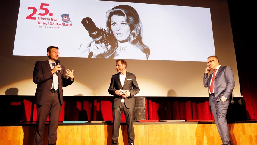 Eröffnung im großen Saal des Gemeinschaftshauses unter dem Plakat von Ehrenpreisträgerin Senta Berger: Oberbürgermeister Marcus König, Moderator Tim Seyfi und Festivaldirektor Adil Kaya (von links).