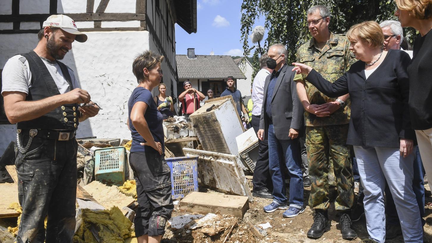 Bundeskanzlerin Angela Merkel und Malu Dreyer, Ministerpräsidentin von Rheinland-Pfalz, sprechen mit betroffenen Anwohner bei ihrer Besichtigung des vom Hochwasser verwüsteten Dorfs Schuld bei Bad Neuenahr-Ahrweiler. 