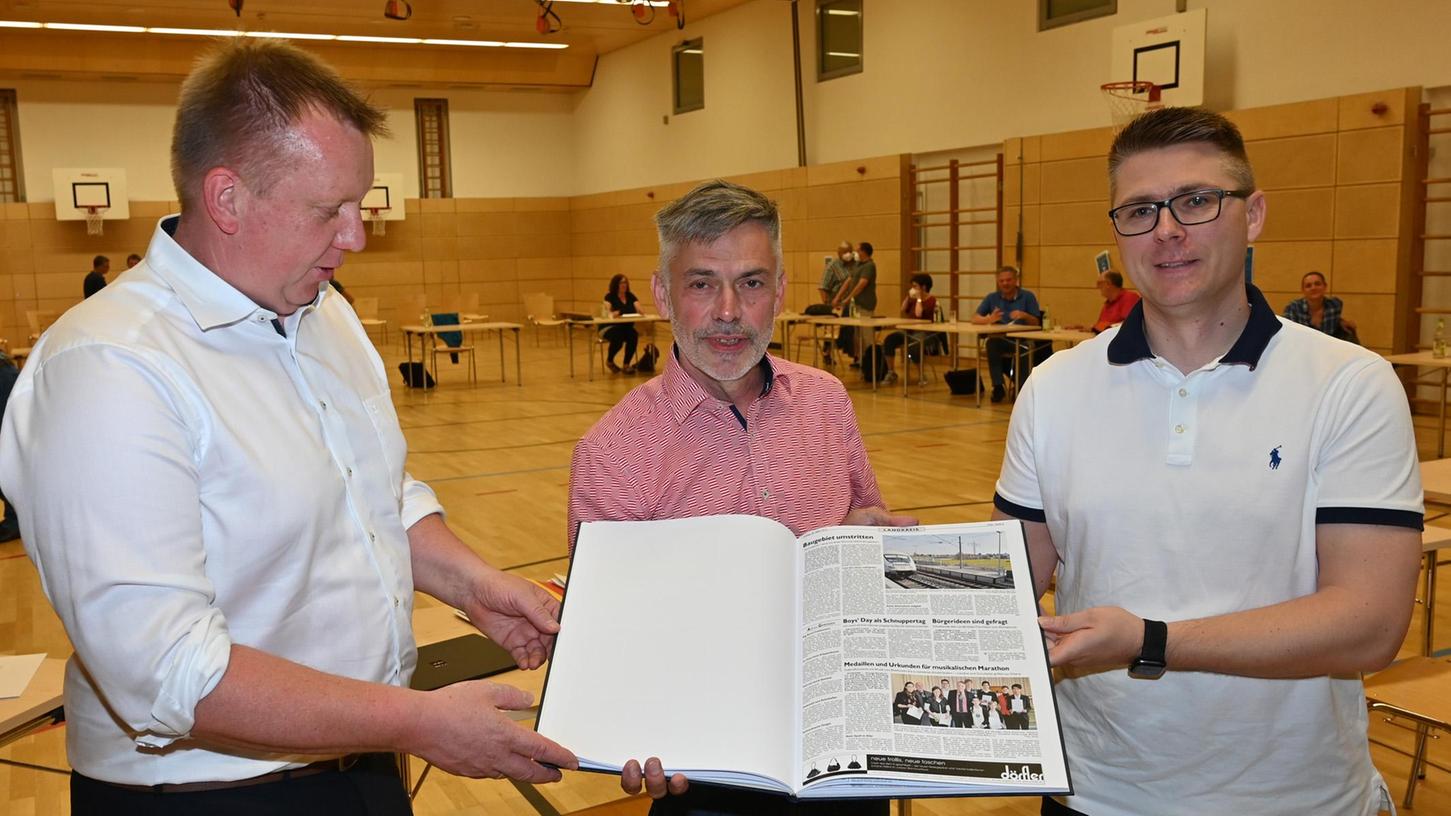 Der Geschäftsleiter im Bubenreuther Rathaus, Helmut Racher (Mitte) ist in den Ruhestand verabschiedet worden. Sein Nachfolger Tobias Zentgraf (r.) und Bürgermeister Norbert Stumpf haben ihm einen Band mit Artikeln aus den Erlanger Nachrichten geschenkt, in denen sein 20-jähriges Wirken in der Gemeinde dokumentiert ist.