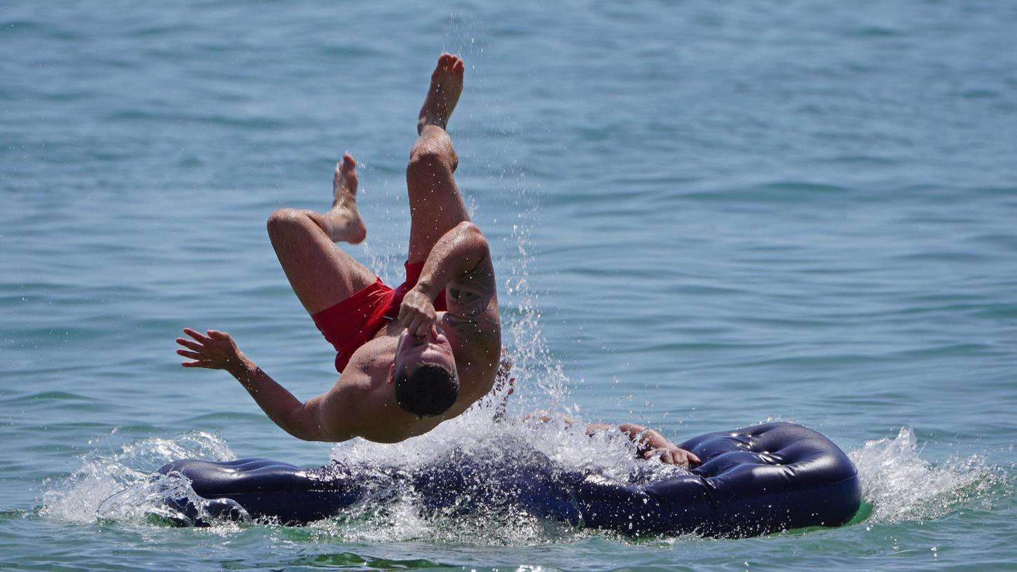 Symbolbild: Ein Mann springt von einer Luftmatratze ins Meer.
