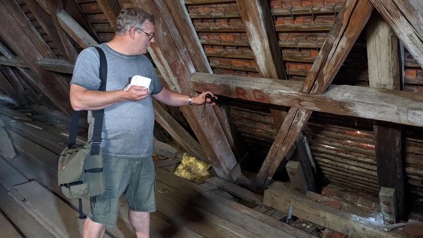 Statiker Stefan Grabmann zeigt mit der Taschenlampe die kritischen Stellen im Dachstuhl über dem Kirchenschiff.