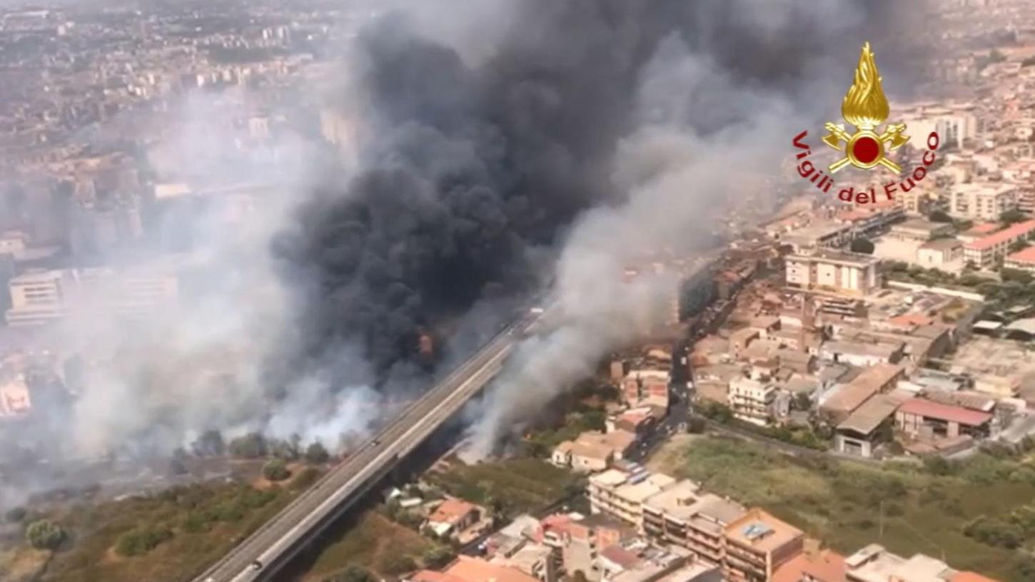 Catania: Blick aus einem Hubschrauber der Feuerwehr auf Brände neben der Via Palermo - dichter Rauch zieht über die Wohnhäuser. In Italien sind die Feuerwehren weiter im Dauereinsatz gegen die lodernden Waldbrände. Allein in Sizilien rückten die Retter 250 Mal aus.