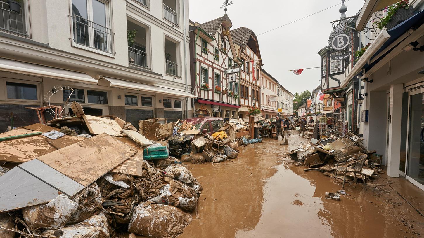 Anwohner und Ladeninhaber versuchen, nach der verheerenden Hochwassernacht ihre Häuser vom Schlamm zu befreien und unbrauchbares Mobiliar nach draußen zu bringen.