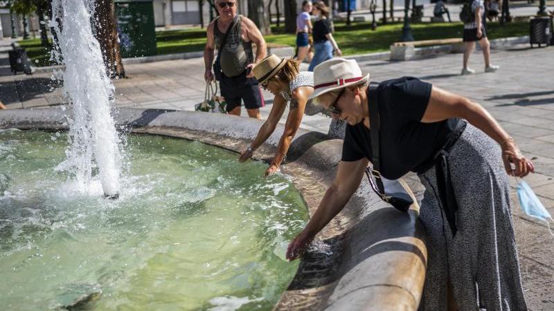 Menschen erfrischen sich bei Temperaturen über 40 Grad mit Wasser aus einem Brunnen auf dem Syntagma-Platz in Athen