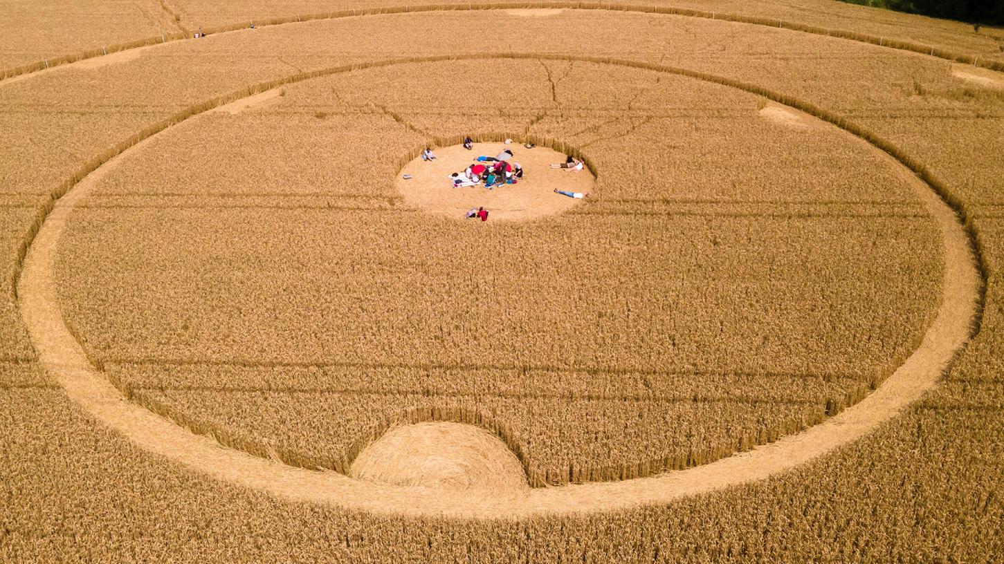 Menschen laufen durch einen Kornkreis in einem Weizenfeld. Die Kreise wurden am Wochenende entdeckt. 