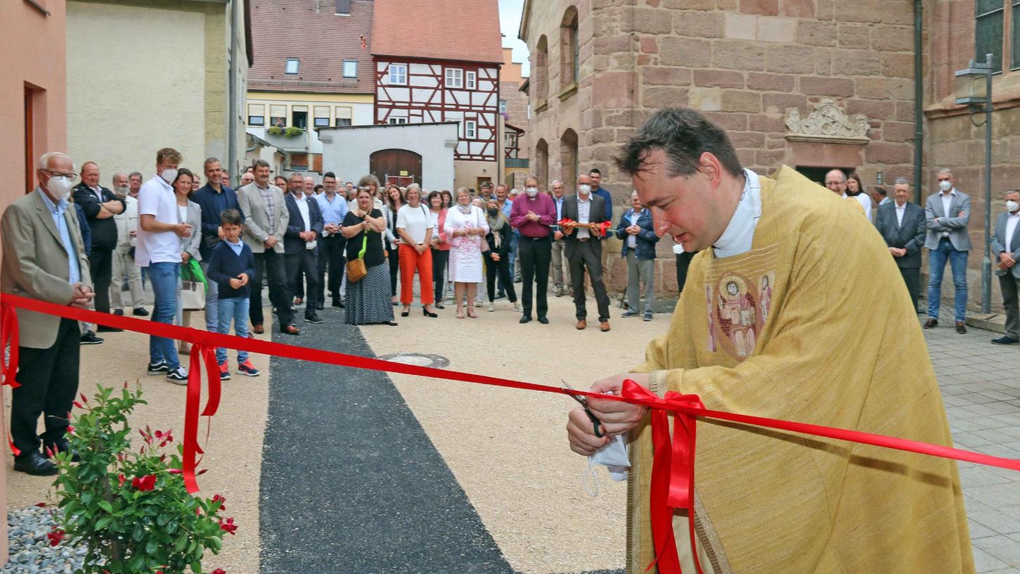 Pfarrer Sebastian Lesch hatte beim Umbau des Hauses selbst mit Hand angelegt und durfte sich nun einreihen, um das rote Eröffnungsband zu durchschneiden. 