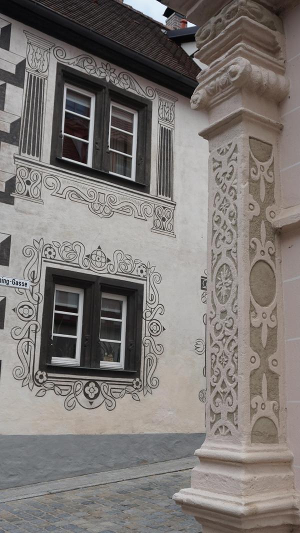In dieser Detailaufnahme kann man neben der aufwendig gestallten Säule der Vogtei auch die prächtige Bemalung des Fürstengasthauses bewundern.