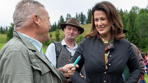 Klaus Steiner, CSU-Landtagsabgeordneter, zeigt Michaela Kaniber (CSU), Staatsministerin für Ernährung, Landwirtschaft und Forsten, während der Hauptalmbegehung eine Einwegspritze (befüllt mit Radler), die er zuvor dem stellvertretenden Ministerpräsidenten und Staatsminister für Wirtschaft, Landentwicklung und Energie, Aiwanger (Freie Wähler), angeboten hatte. Der stellte sich mit kritischen Äußerungen zu Coronaimpfungen ins Abseits und lehnte die Annahme der Spritze ab.
