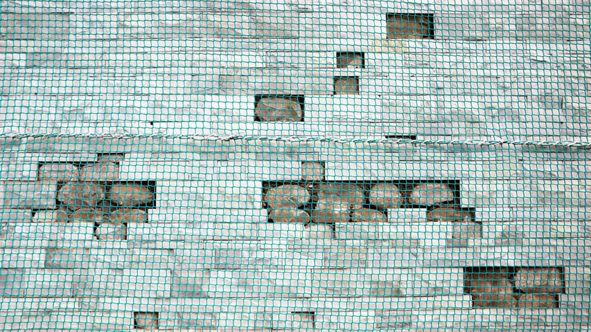 Hinter den Netzen sieht man Backsteine, die aus der Fassade ragen. Es besteht die Gefahr, dass diese runterfallen. Hinter den Netzen sieht man Backsteine, die aus der Fassade ragen. Es besteht die Gefahr, dass diese runterfallen.