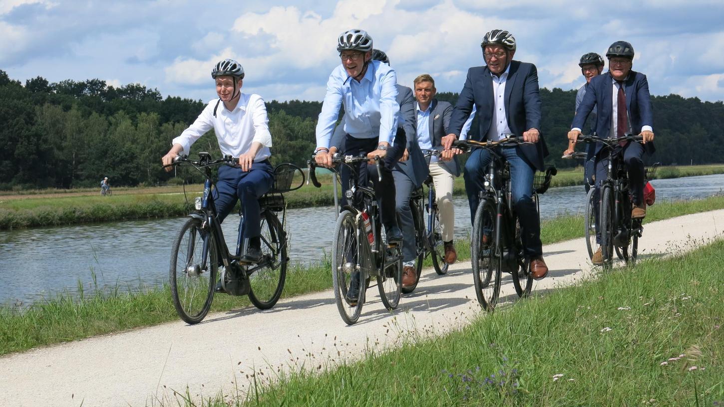 Auf Asphalt wäre es besser: Bundesverkehrsminister Andreas Scheuer (Mitte) und Vertreter der Metropolregion testen bei Baiersdorf die Strecke entlang des Kanals.