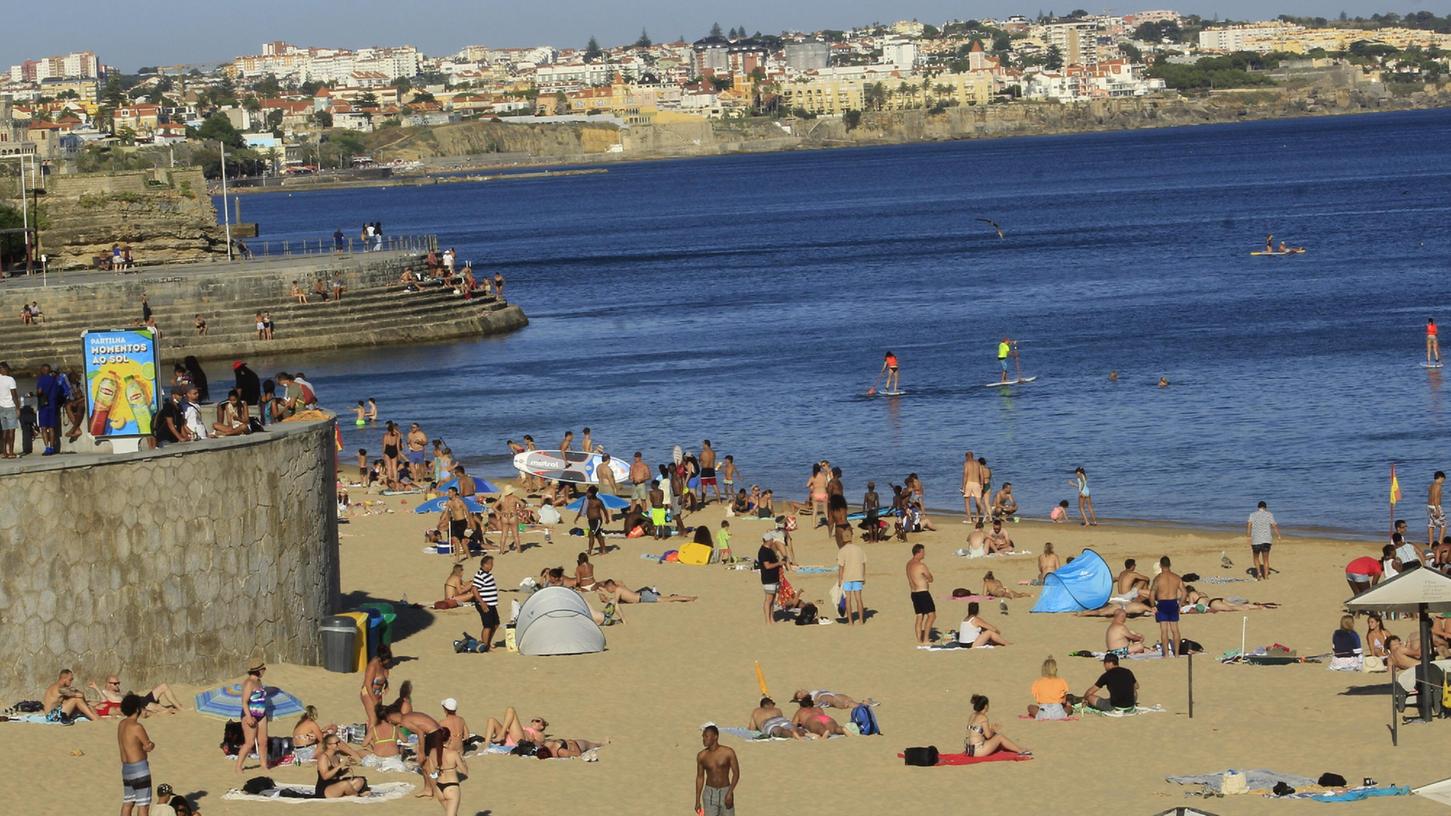 Badegäste stehen am Strand Conceicao in Portugal. Wer in diesen Tagen aus dem Urlaubsland zurück kehrt, muss nicht in Quarantäne. Die Bundesregierung hat im Juli Portugal zum Hochinzidenzgebiet zurückgestuft.