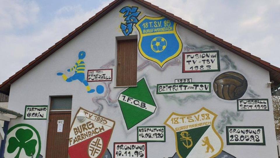 So sieht das Sportheim "Auf der Tulpe" des TSV 1895 Burgfarrnbach aus. Vereinsmitglieder haben die bisherigen Wappen und das neue (ganz oben) als Graffiti an die Wand gemalt. Das Kleeblatt links symbolisiert die Kooperation mit der SpVgg Greuther Fürth.