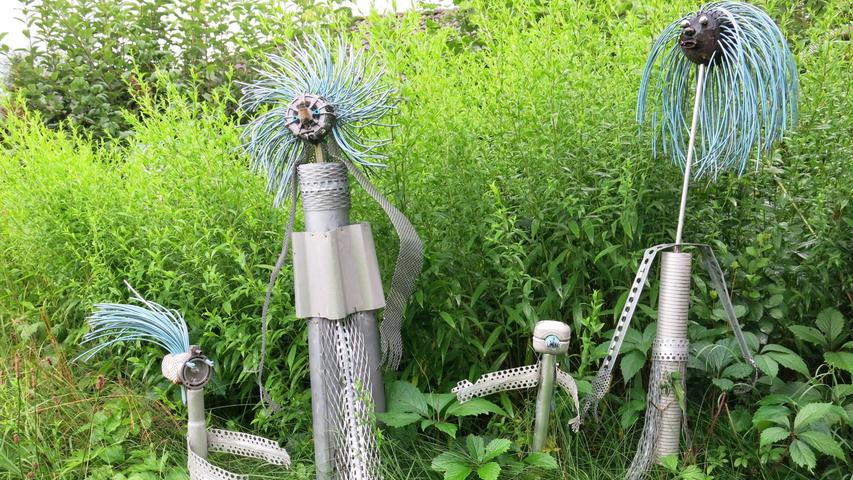 Sogar Außerirdische mit wilden Haaren aus isoliertem Draht haben ihren Platz zwischen Gräsern, Blumen und Büschen gefunden. Sogar Außerirdische mit wilden Haaren aus isoliertem Draht haben ihren Platz zwischen Gräsern, Blumen und Büschen gefunden.