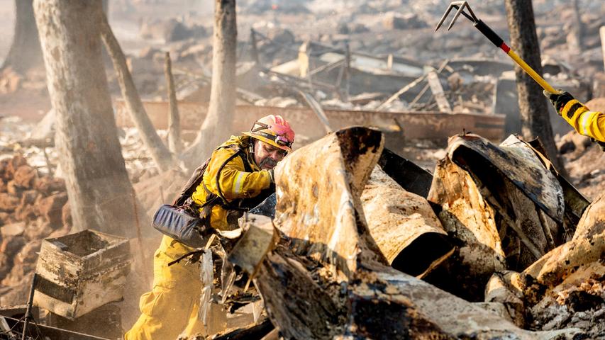 Feuerwehrmann Jesse Viescas durchsucht Schutt eines verbrannten Hauses in den Cache Creek Mobile Home Estates, wo Waldbrände des Cache-Feuers Dutzende von Häusern verwüstet haben. 