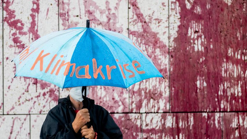 Bei Protestaktion von Umweltaktivisten vor dem Konrad-Adenauer-Haus wurde die CDU-Parteizentrale mit Kunstblut besprüht.  Ein Teilnehmer hält einen Regenschirm mit der Aufschrift "Klimakrise". 