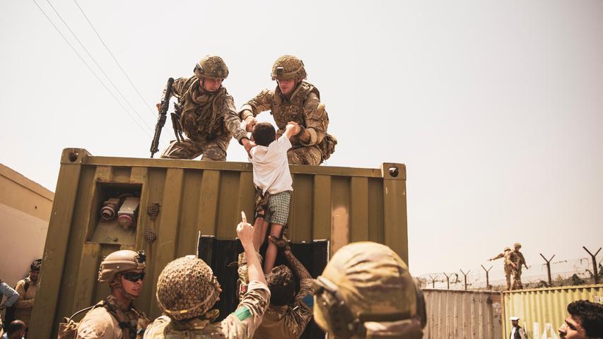  In diesem vom US Marine Corps zur Verfügung gestellten Foto helfen britische und türkische Koalitionstruppen zusammen mit US-Marines einem Kind während einer Evakuierung am Hamid Karzai International Airport.