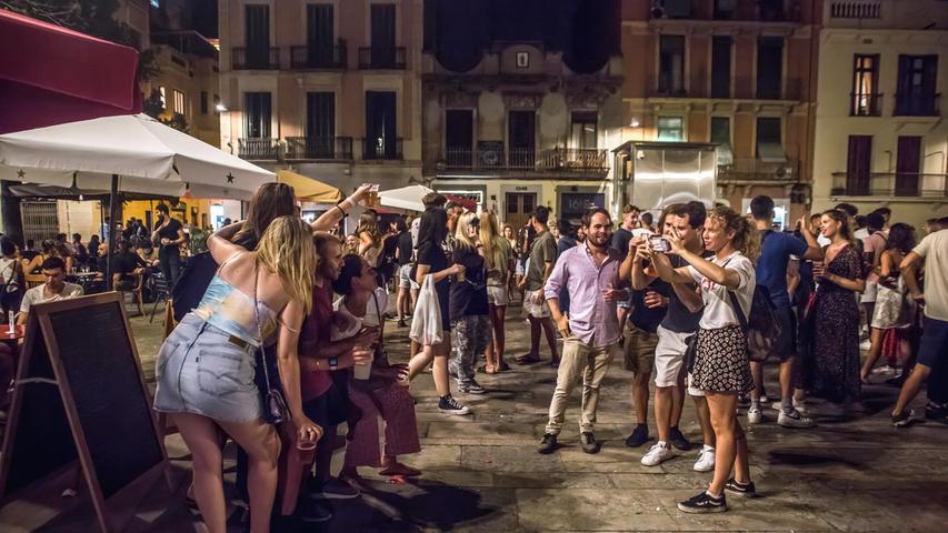 Menschen posieren für ein Foto, während sie auf einer Straße in Barcelona trinken. Der Oberste Gerichtshof von Katalonien (TSJC) hat das Ende der nächtlichen Ausgangssperre in Barcelona festgesetzt, zeitgleich mit der Woche, in der das traditionelle Fest des Viertels Gracia gefeiert wird.