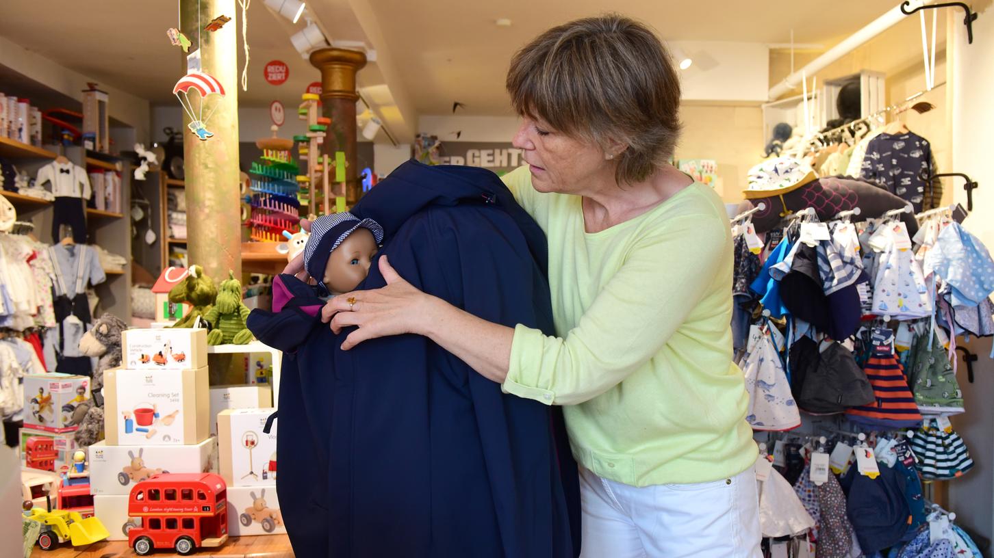 Sylvia Galster vom Geschäft "Wundervoller Start" in Fürth zeigt anhand einer Puppe, wie ein Baby unter einer erweiterbaren Jacke getragen werden kann.