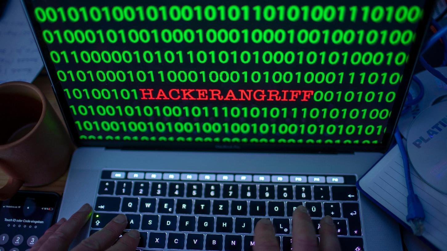 Das wünscht sich kein Unternehmen: Zwischen dem Binärcode auf einem Laptopmonitor ist das Wort "Hackerangriff" zu lesen. 