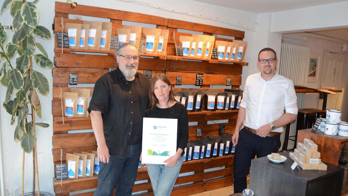 Schwabachs "Blaues Haus Kaffee" kann sich nun "klimapositives Unternehmen" nennen. Peter Güttinger und Heather Denny mit dem Zertifikat. "Das zeigt, dass wir unsere Hausaufgaben gemacht haben." Oberbürgermeister Peter Reiß (rechts) gratuliert dazu.   