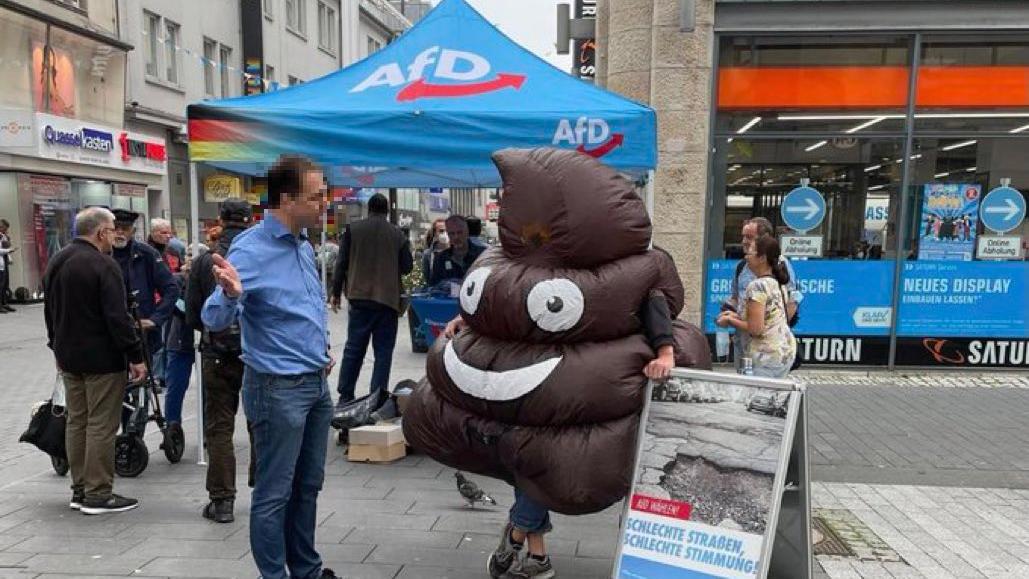 Mensch im Kothaufen-Kostüm protestiert gegen die AfD