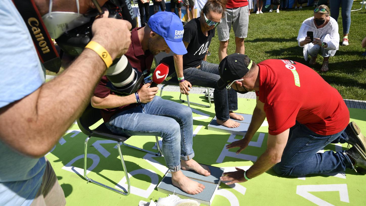 Nicht Ehrung, sondern Verewigung der Sieger: Bürgermeister Ralph Edelhäußer nimmt Fußabdrücke von Patrick Lange und Anne Haug, die in den „Walk of Triathlon“ eingebaut werden.